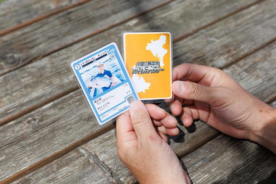 写真：カードゲームのカードを２枚持っている手。青いカードと黄色のカード。